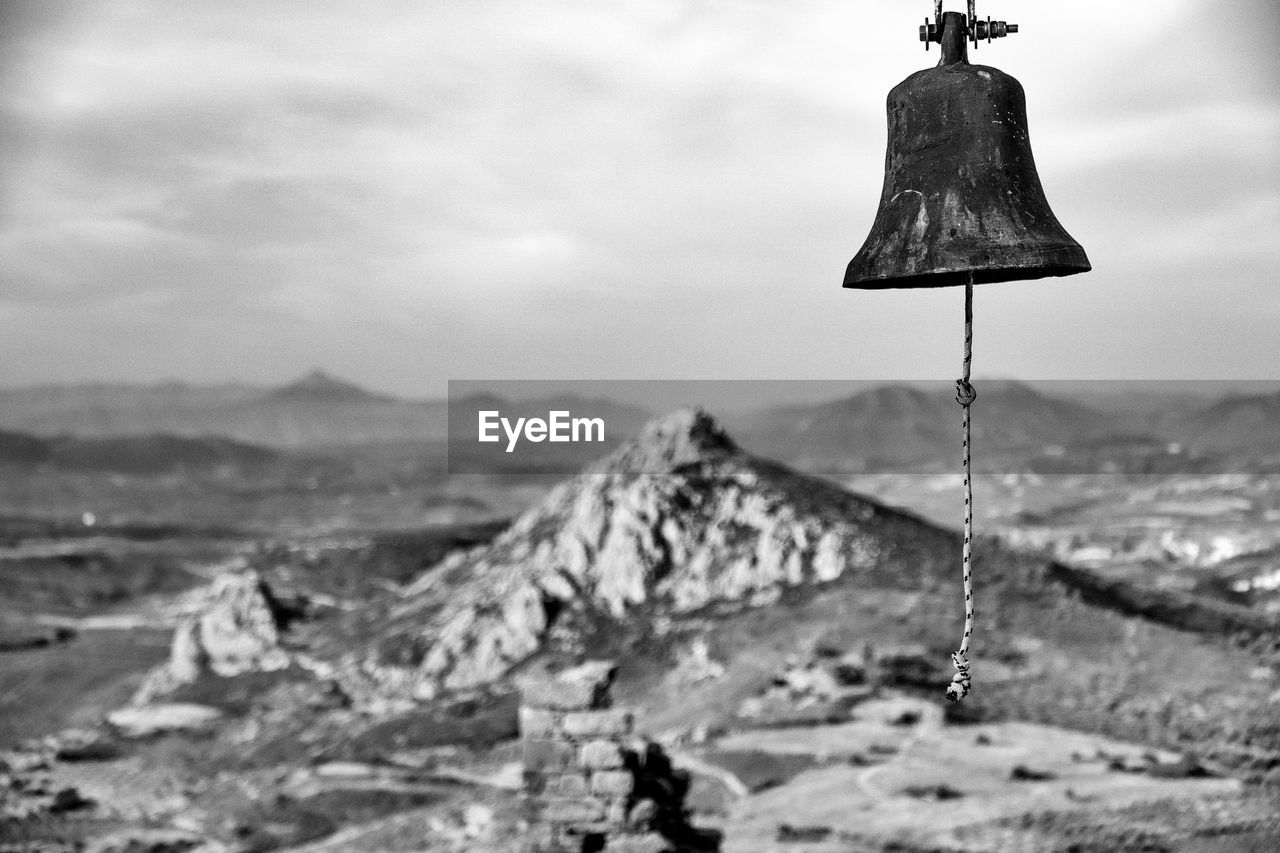 Old bell over landscape against sky