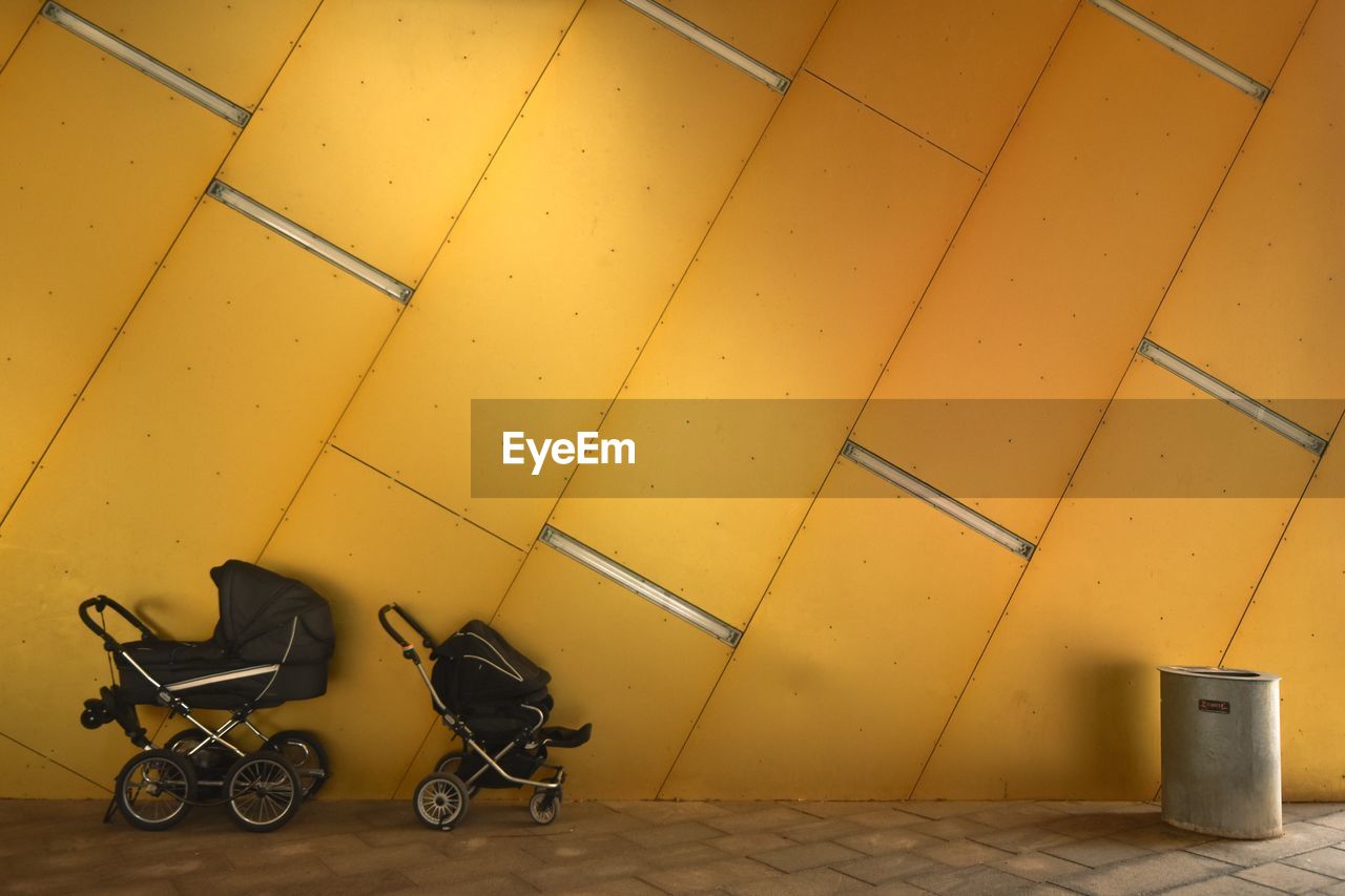 Baby carriage against yellow wall