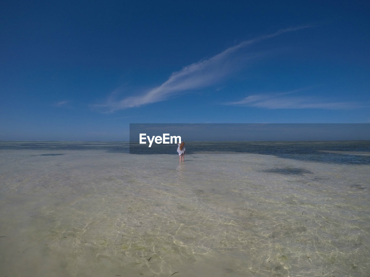 Rear view of woman walking at beach against sky