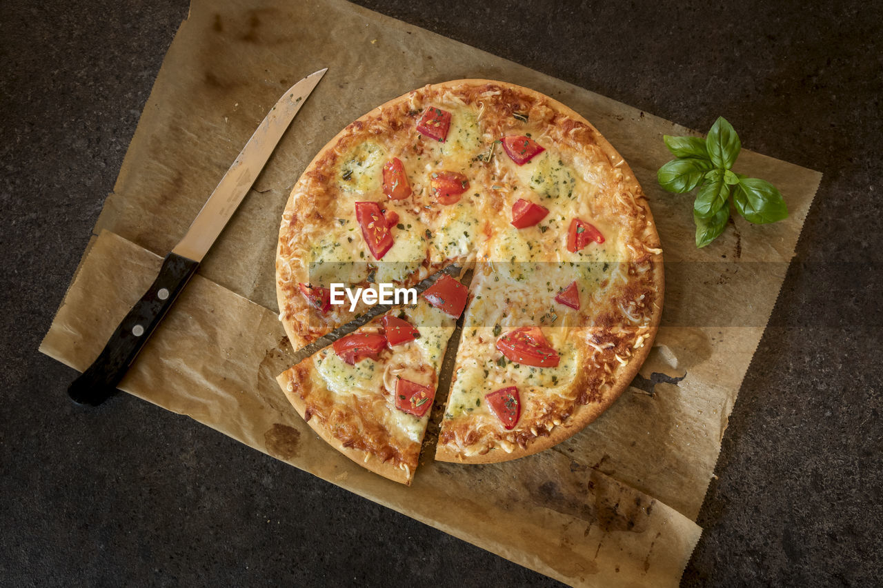 HIGH ANGLE VIEW OF PIZZA ON CUTTING BOARD ON TABLE