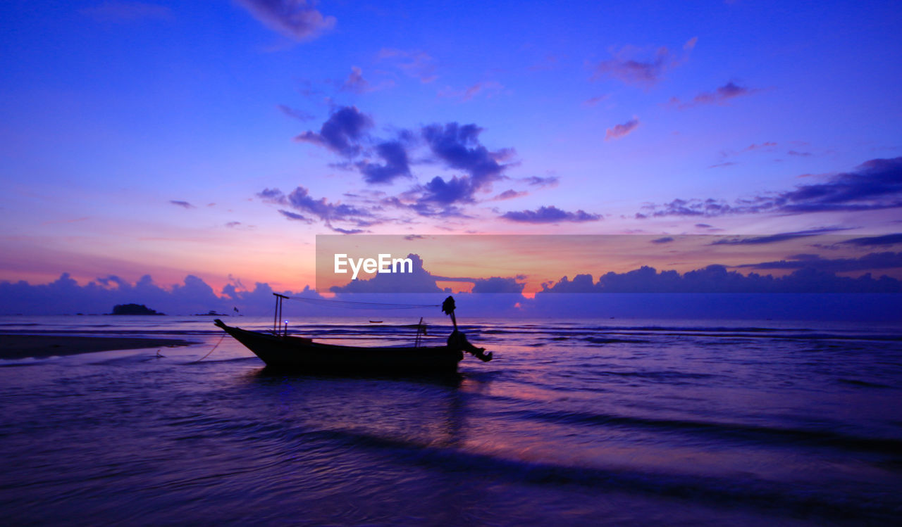 Amazing silhouette of fisherman yacht during breathtaking sunrise at cherating, pahang, malaysia.