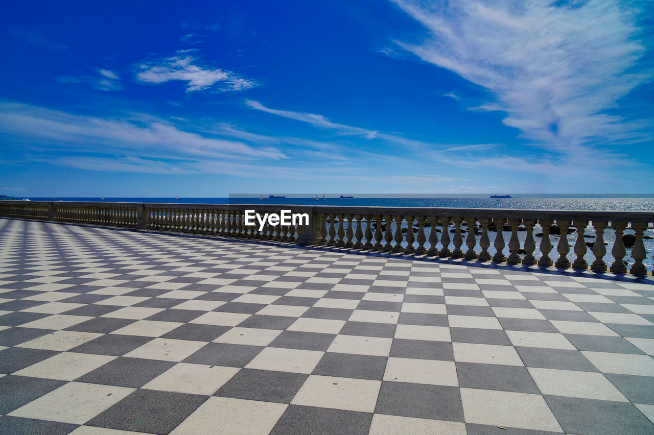 Scenic view of boulevard at sea against blue sky