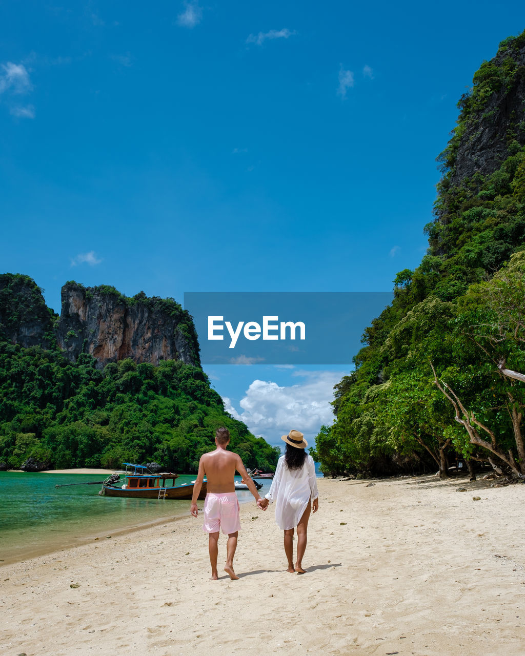 rear view of woman walking at beach against sky