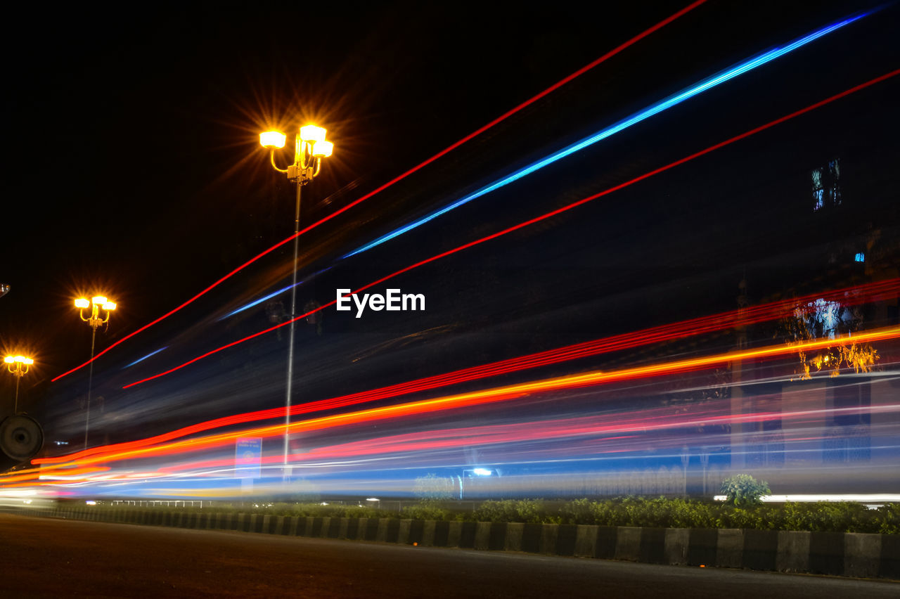 Light trails on street against sky at night