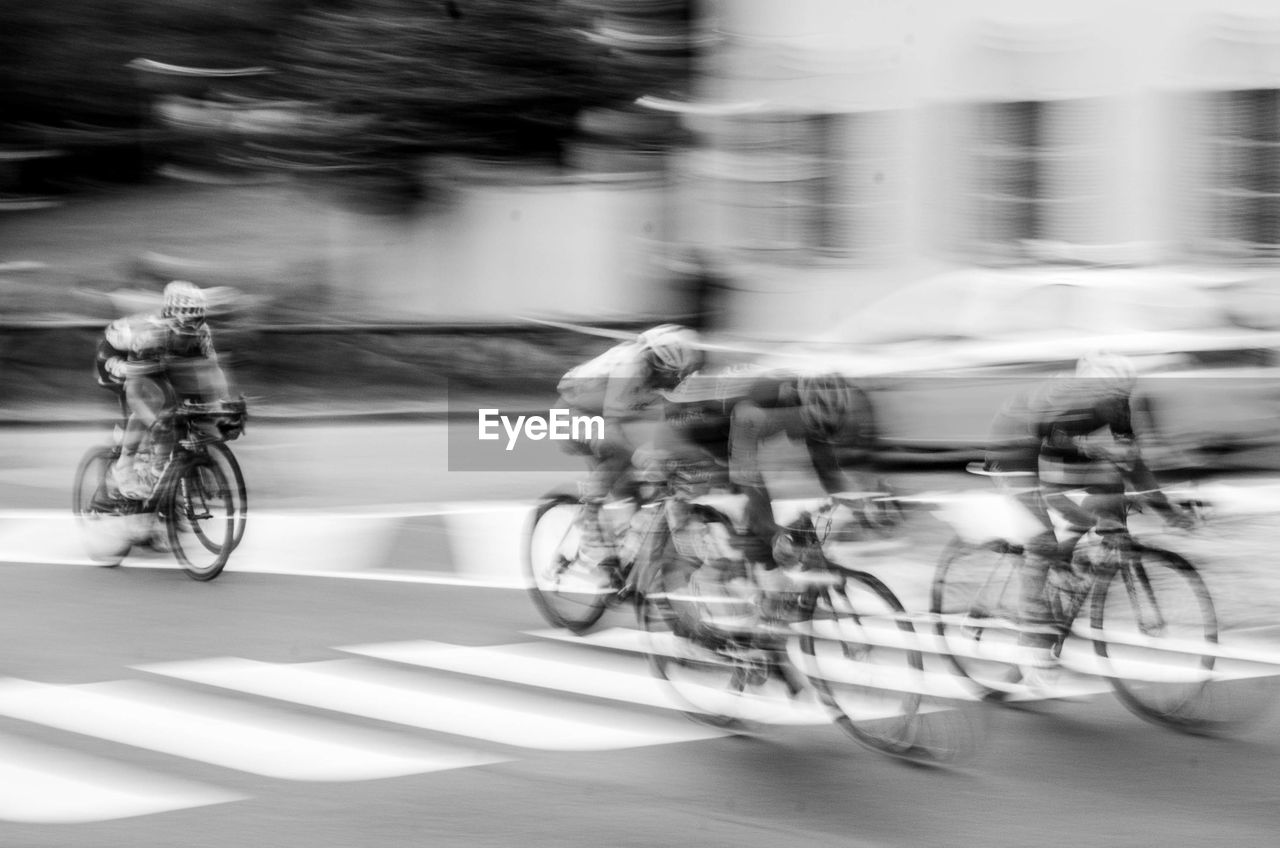 Blurred motion of people riding bicycle on road