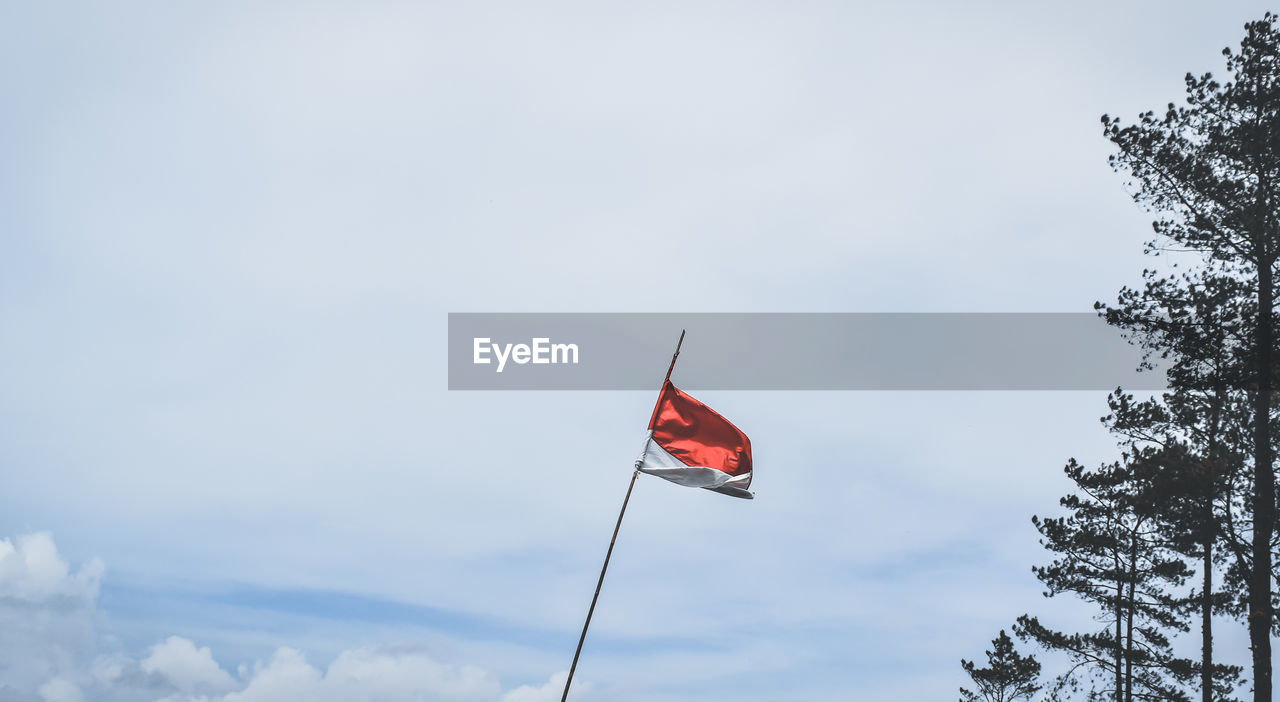 LOW ANGLE VIEW OF RED FLAGS AGAINST SKY
