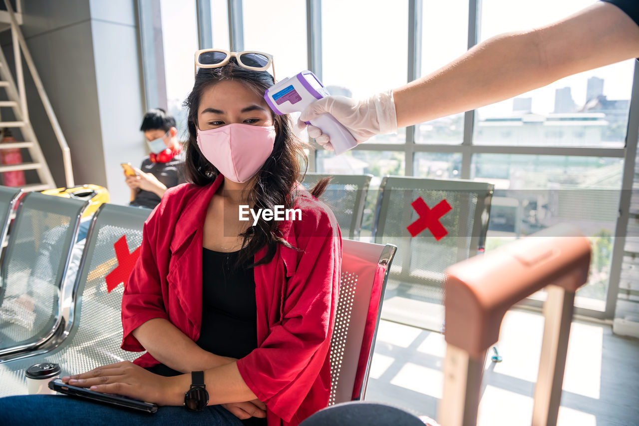 Cropped image of hand checking temperature of woman at airport