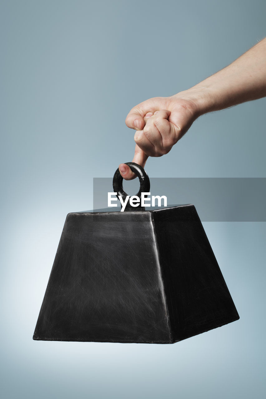 Close-up of hand holding metal against gray background