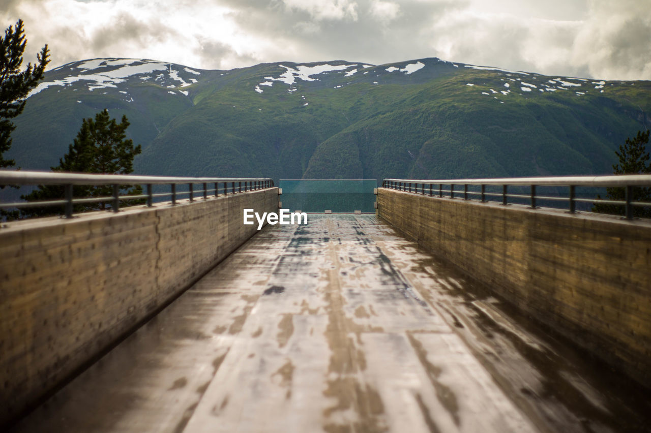 Footbridge leading towards mountains during winter