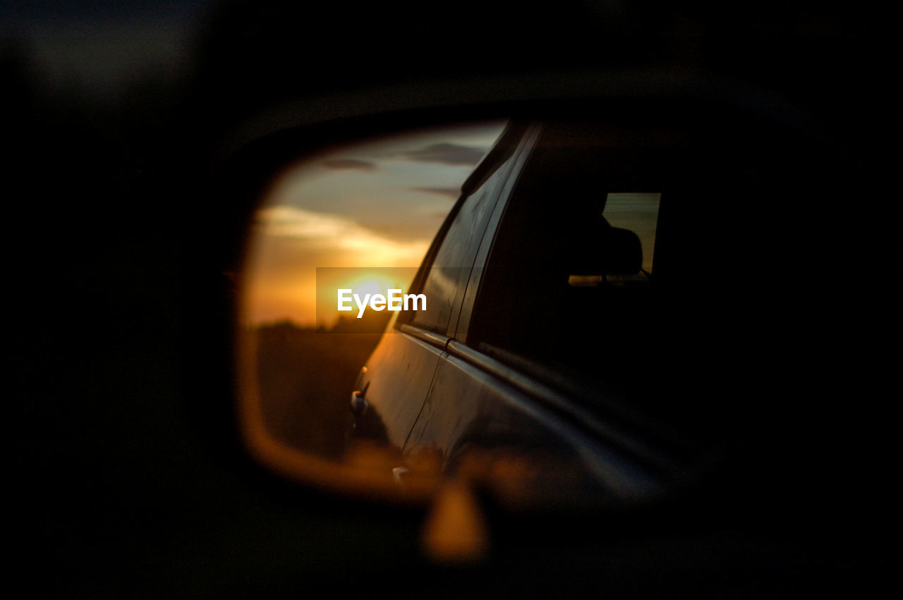 Reflection of car on side-view mirror at sunset