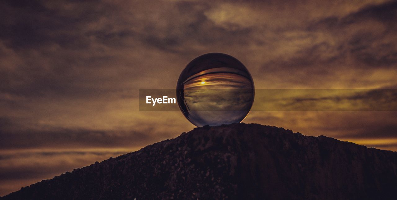 Low angle view of crystal ball against sky during sunset