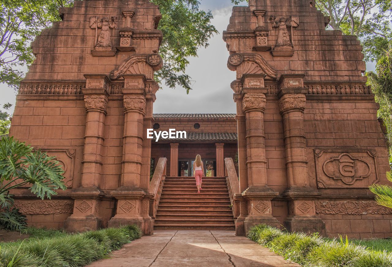 Rear view of woman climbing steps at temple