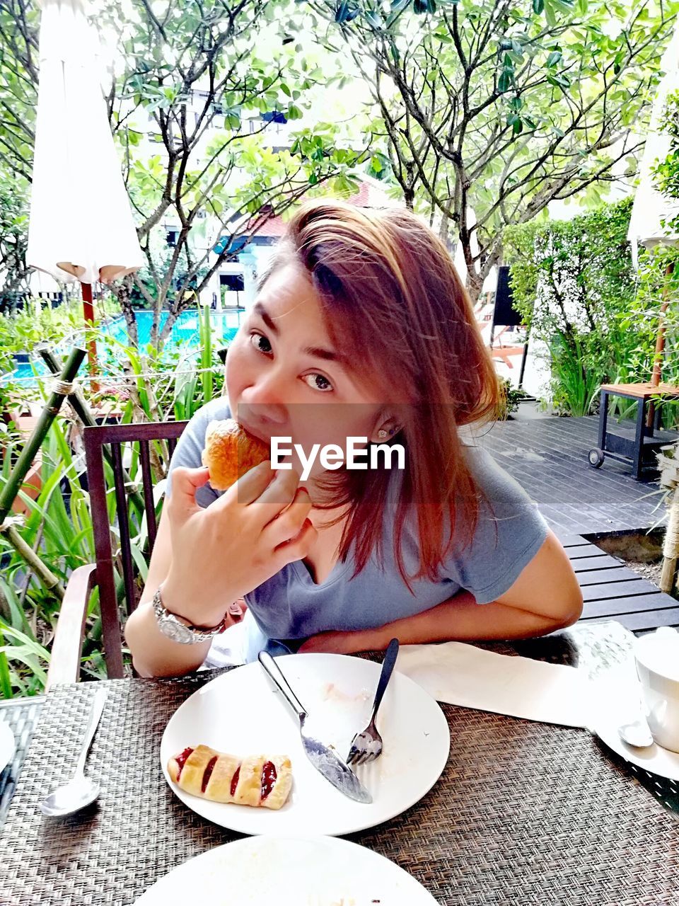 Portrait of young woman eating food at cafe