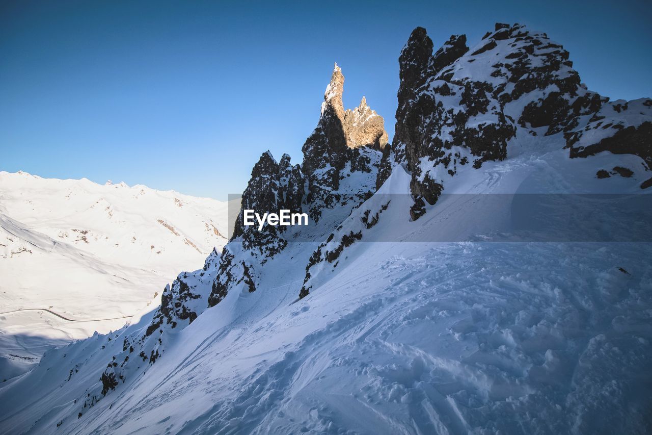 Low angle view of snow mountains against clear blue sky