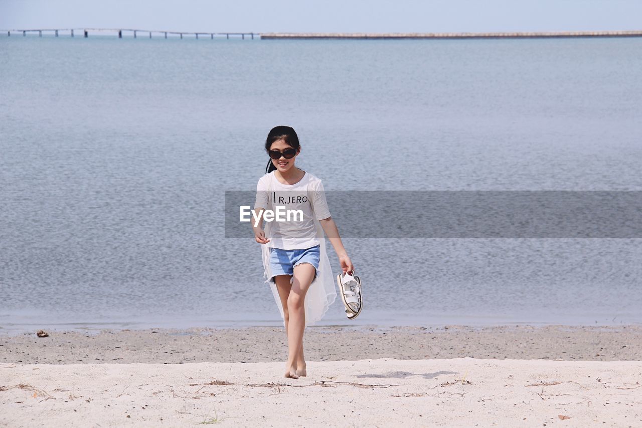 Full length portrait of happy girl walking at beach