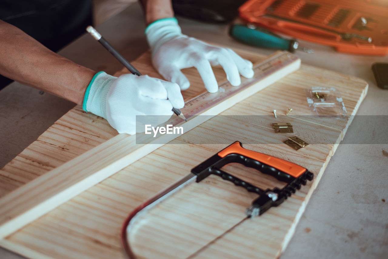 HIGH ANGLE VIEW OF WORKER WORKING ON WOODEN TABLE