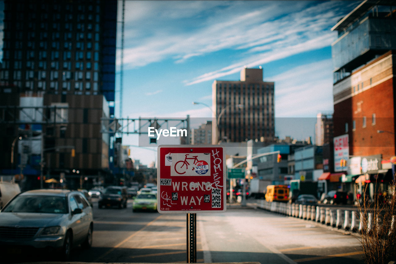 Road sign in city against sky