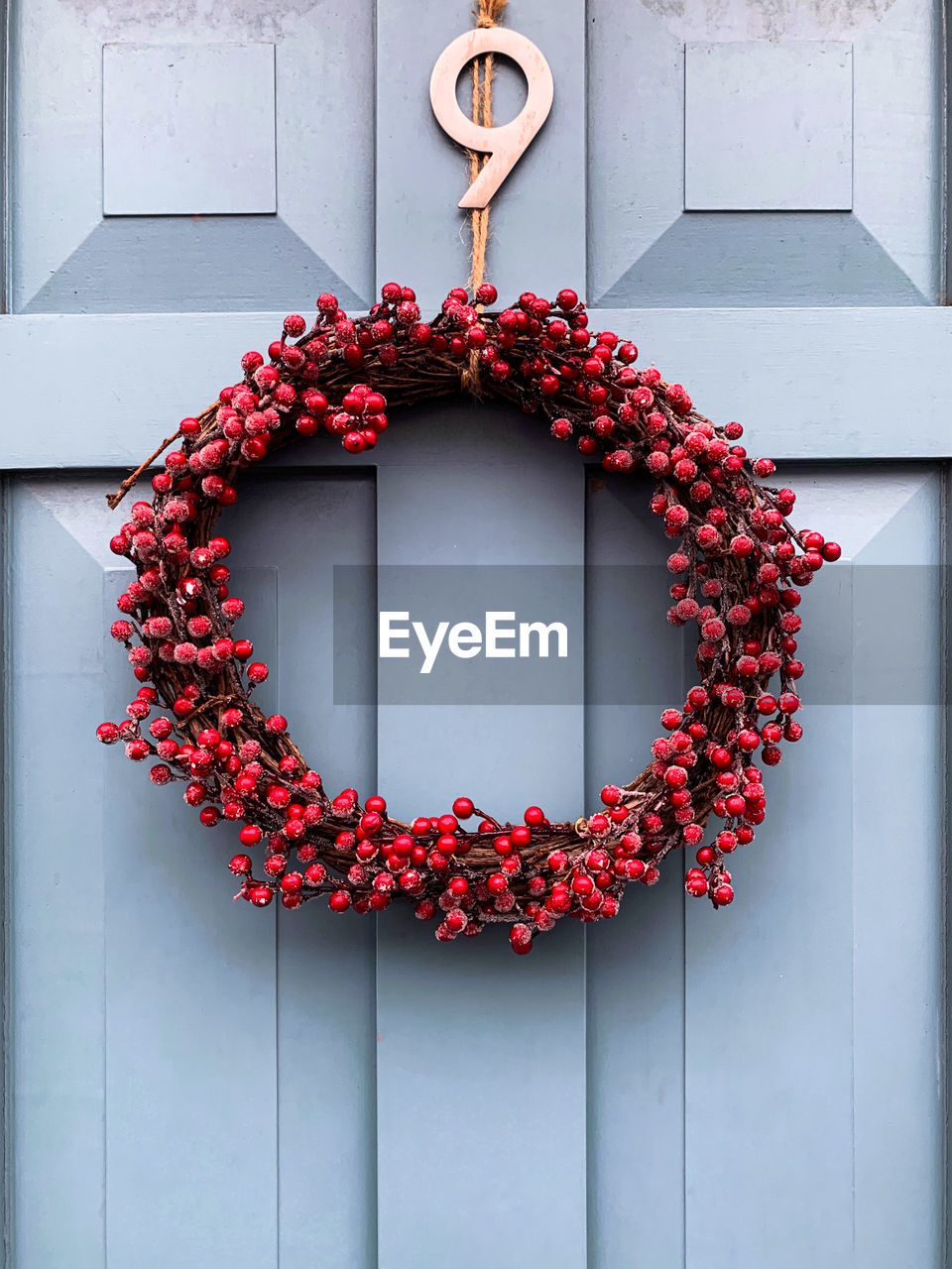 Elegant christmas wreath decorated red berries and tree sticks on a blue wooden door