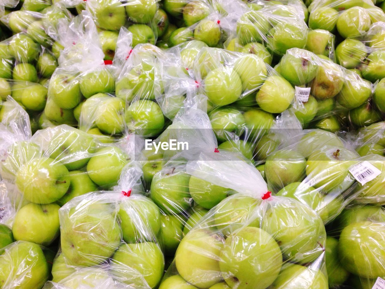 Full frame shot of granny smith apples packed in plastic at market for sale