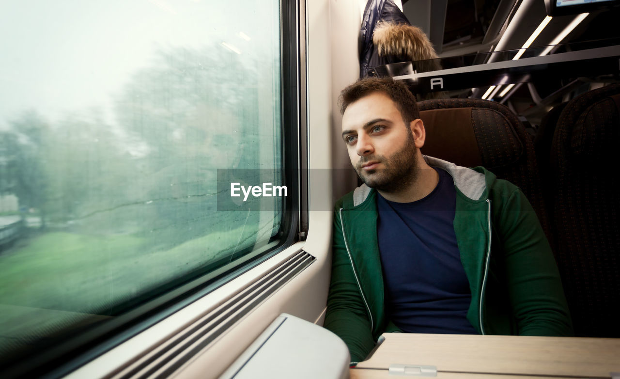 Man looking through window in train