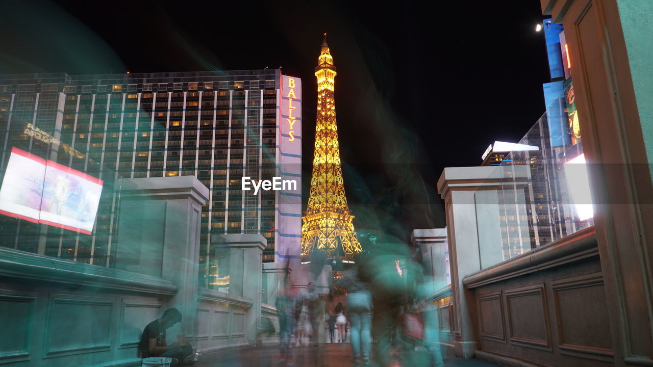 LOW ANGLE VIEW OF ILLUMINATED BUILDINGS AGAINST SKY AT NIGHT