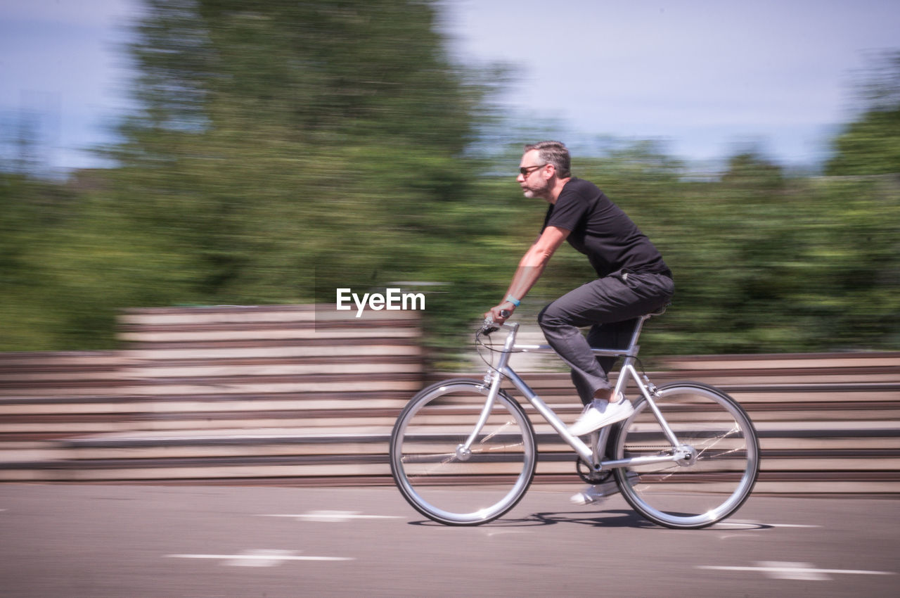 Blurred motion of man riding bicycle on road