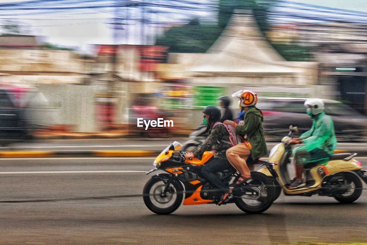 Rear view of man riding motor scooter on road