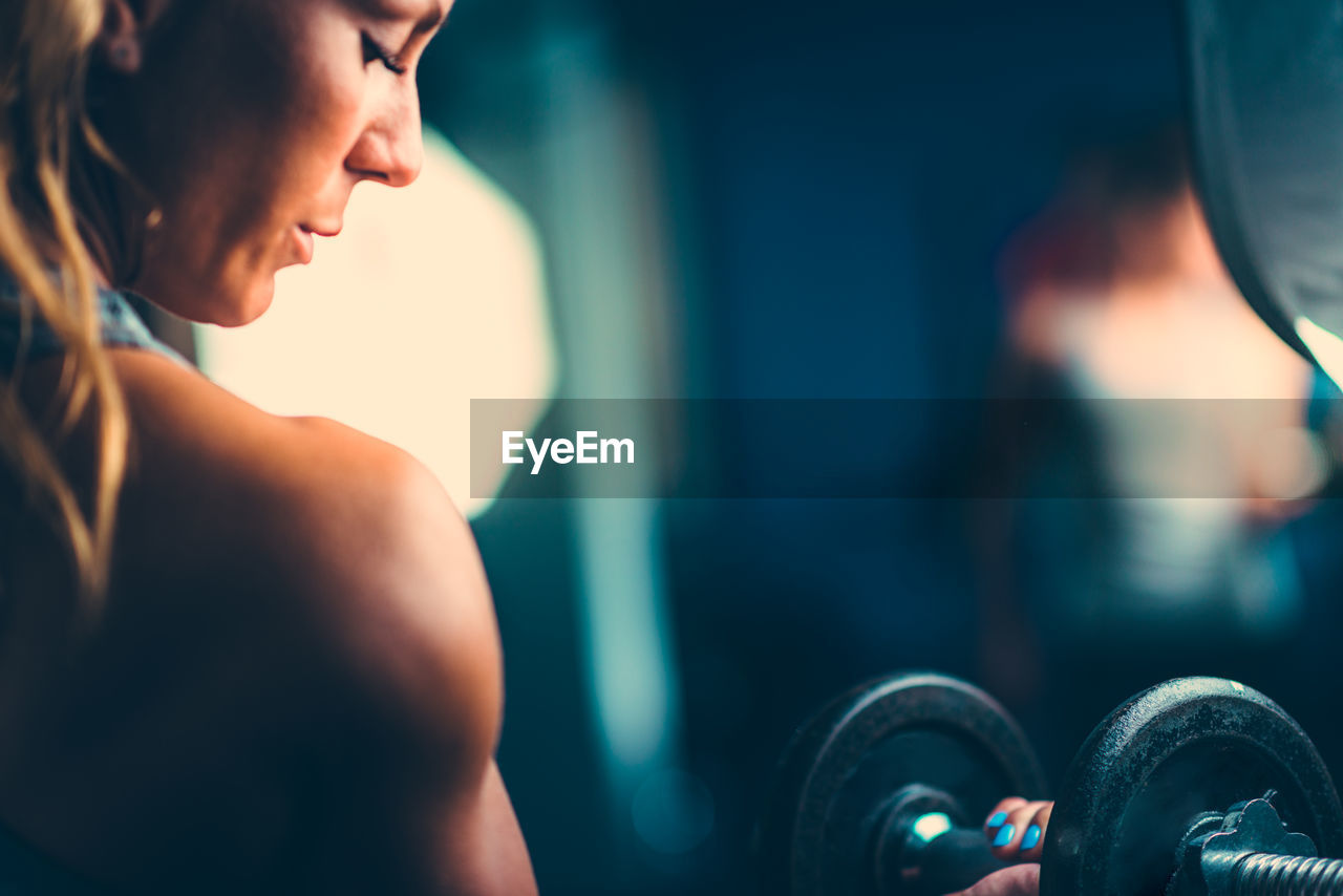 Close-up of mid adult woman lifting dumbbell