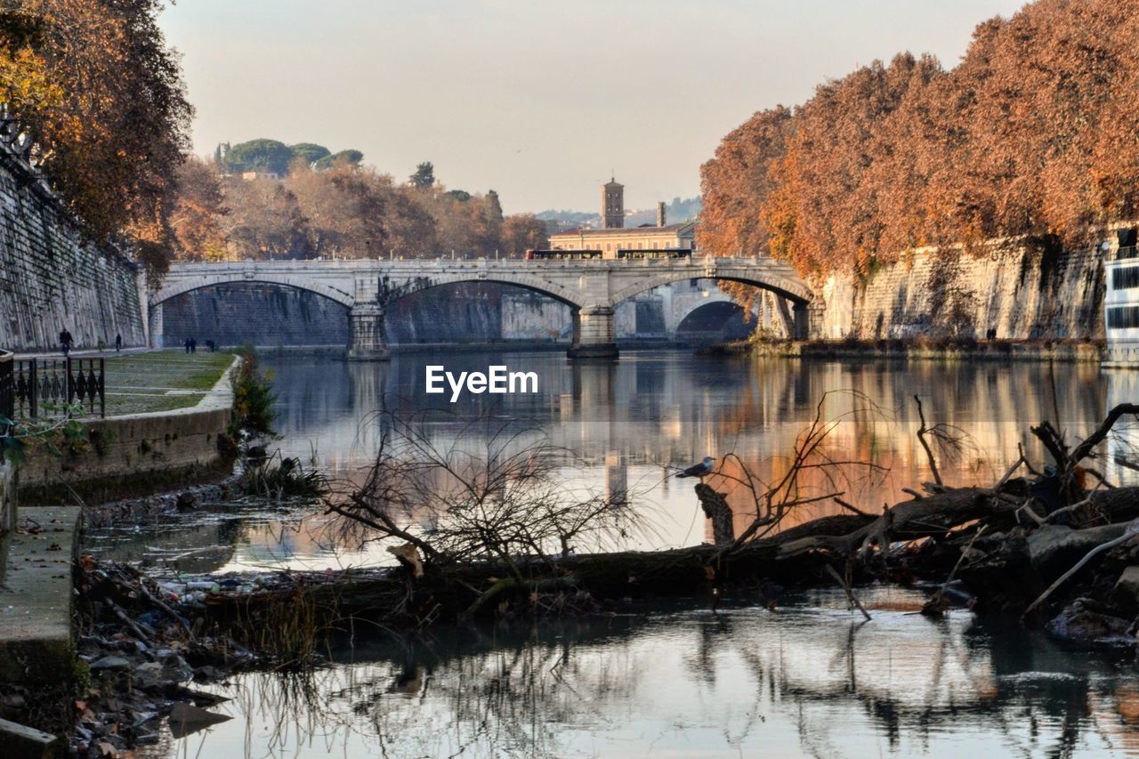 BRIDGE OVER RIVER BY BUILDINGS AGAINST SKY