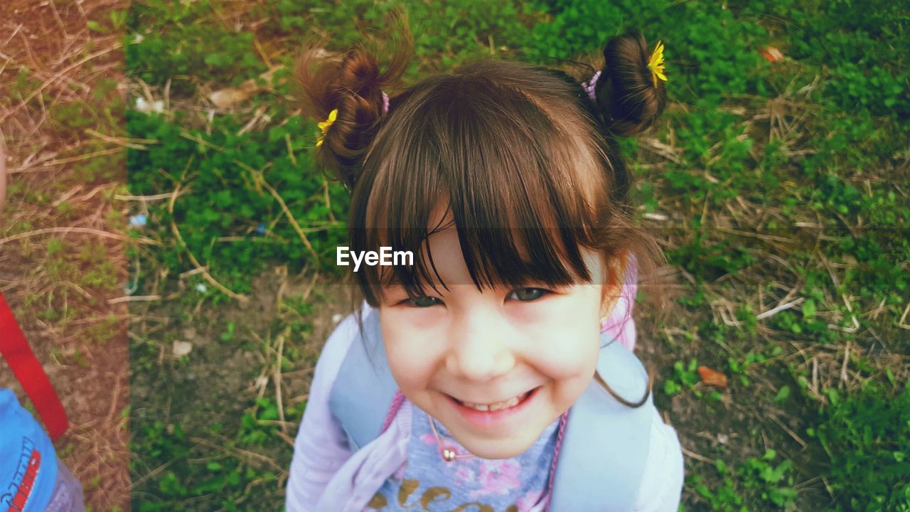 PORTRAIT OF A GIRL LYING ON GRASSY FIELD