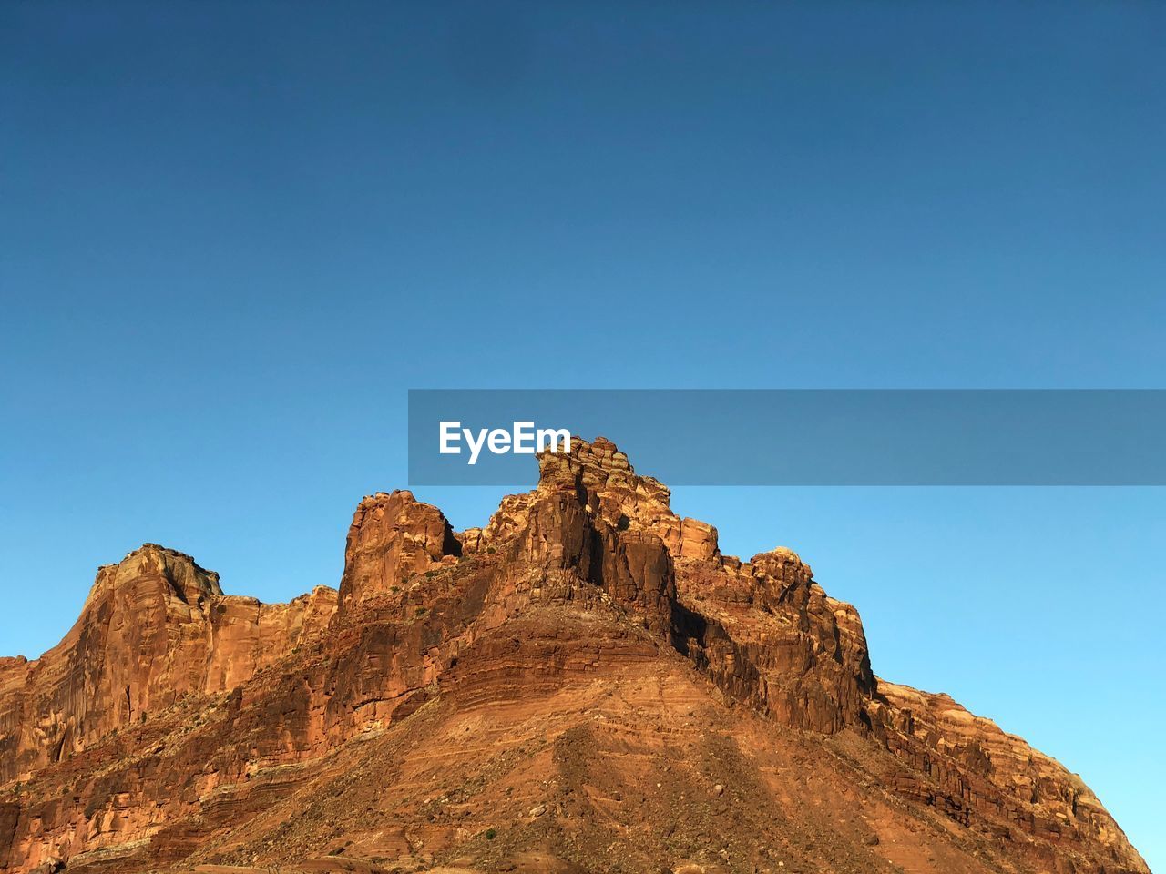 Low angle view of rock formation against clear blue sky