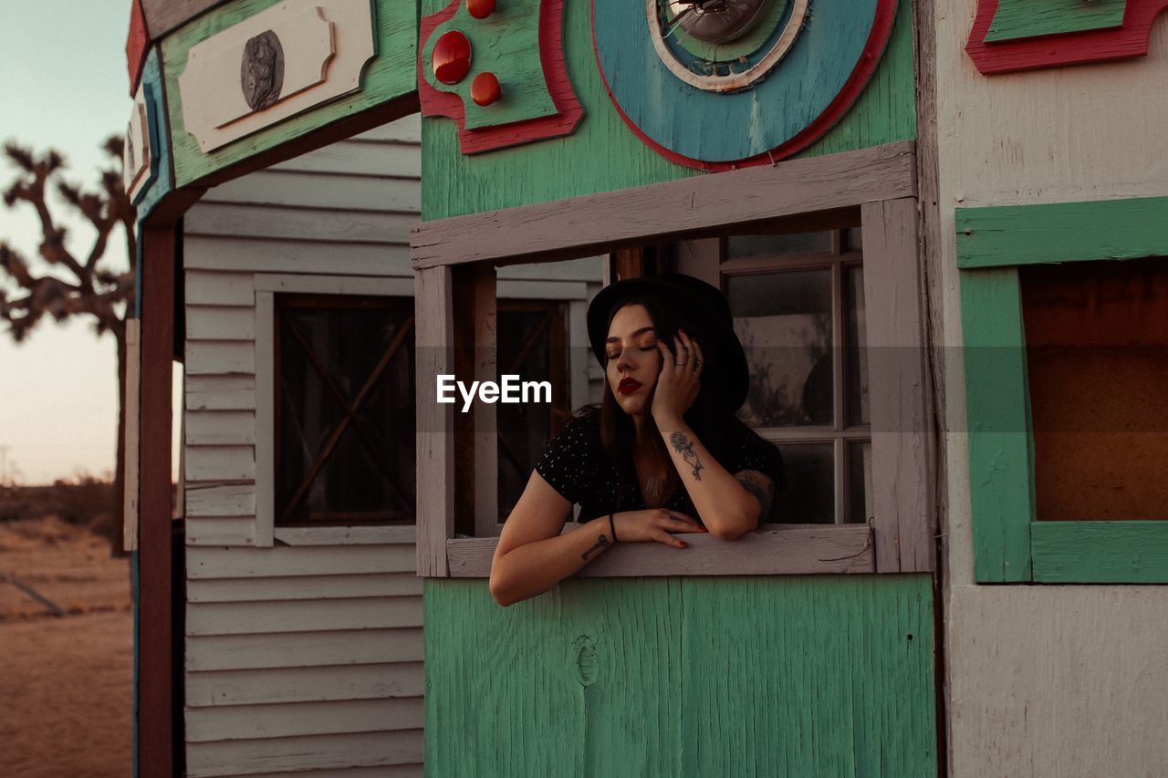 Young woman with eyes closed on window sill