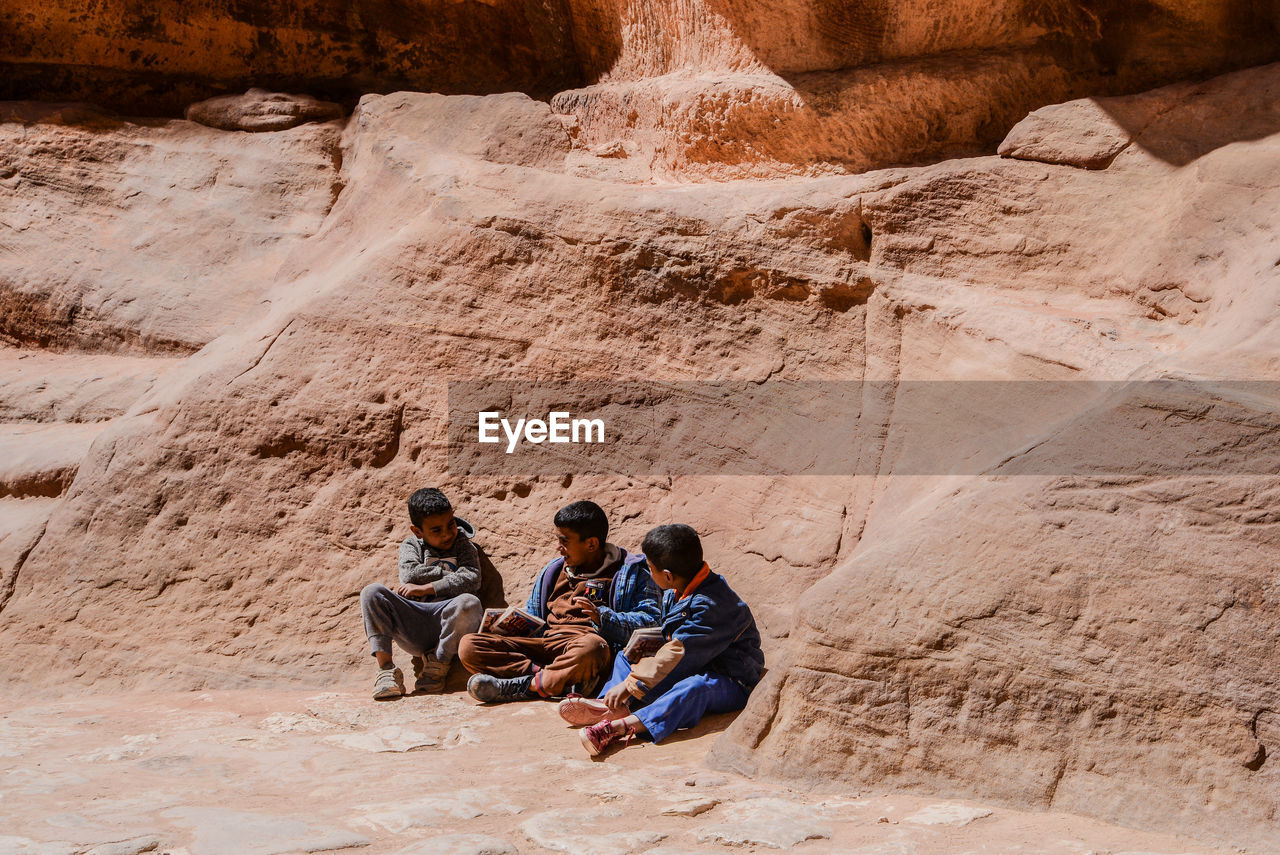 GROUP OF PEOPLE SITTING ON ROCKS