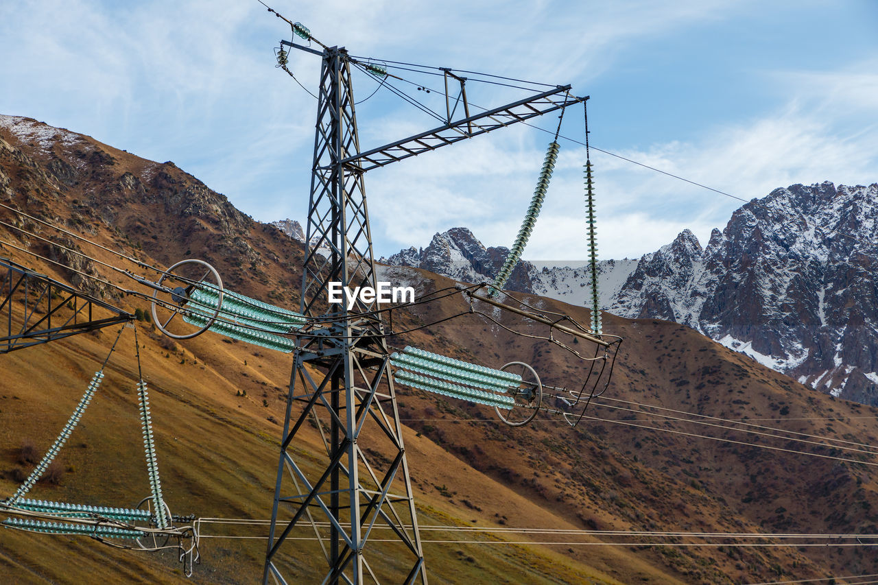 ELECTRICITY PYLON AGAINST SNOWCAPPED MOUNTAINS AGAINST SKY