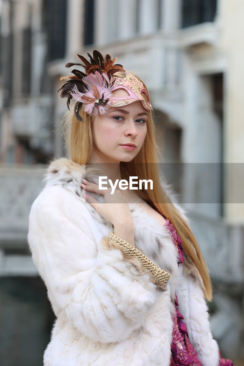 Portrait of beautiful young woman wearing fur coat at carnival