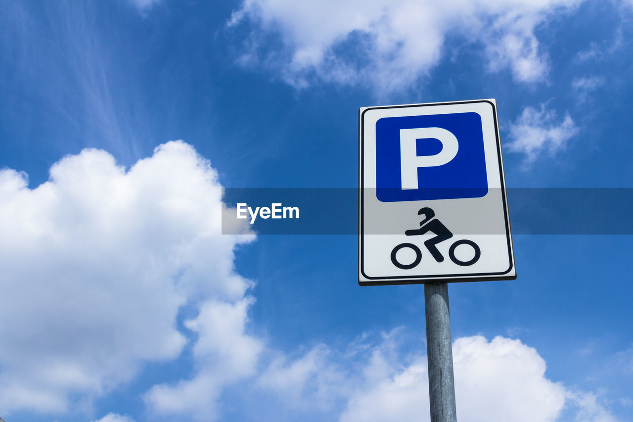 Low angle view of parking sign against cloudy sky