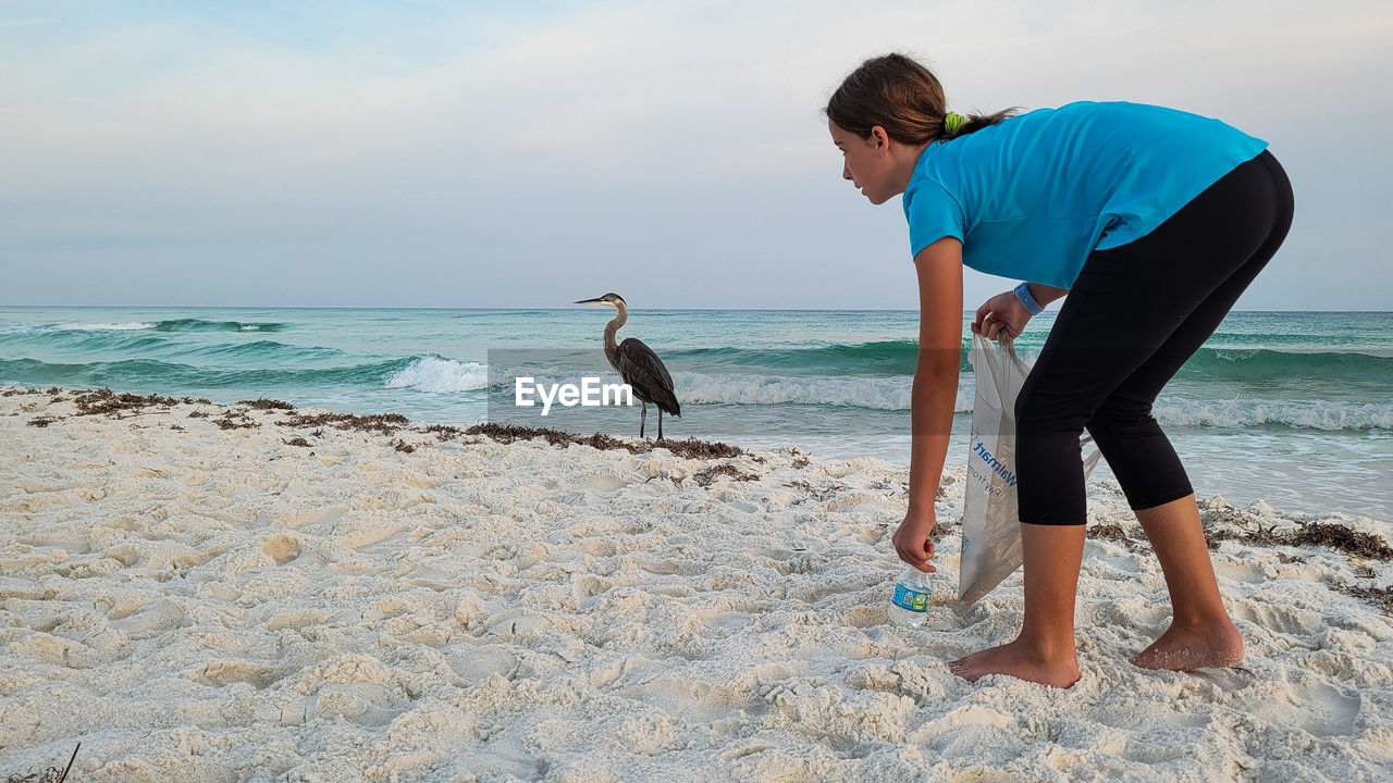 sea, water, beach, land, vacation, shore, ocean, sand, sky, nature, adult, animal, full length, men, horizon over water, one person, horizon, animal themes, leisure activity, holiday, wave, coast, standing, body of water, beauty in nature, one animal, bird, casual clothing, trip, day, side view, lifestyles, wildlife, scenics - nature, animal wildlife, outdoors, tranquility, person, idyllic, clothing, young adult, travel