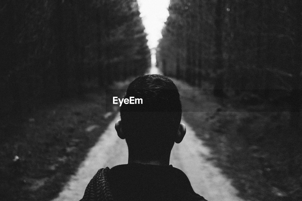 Close-up of man standing on road amidst trees