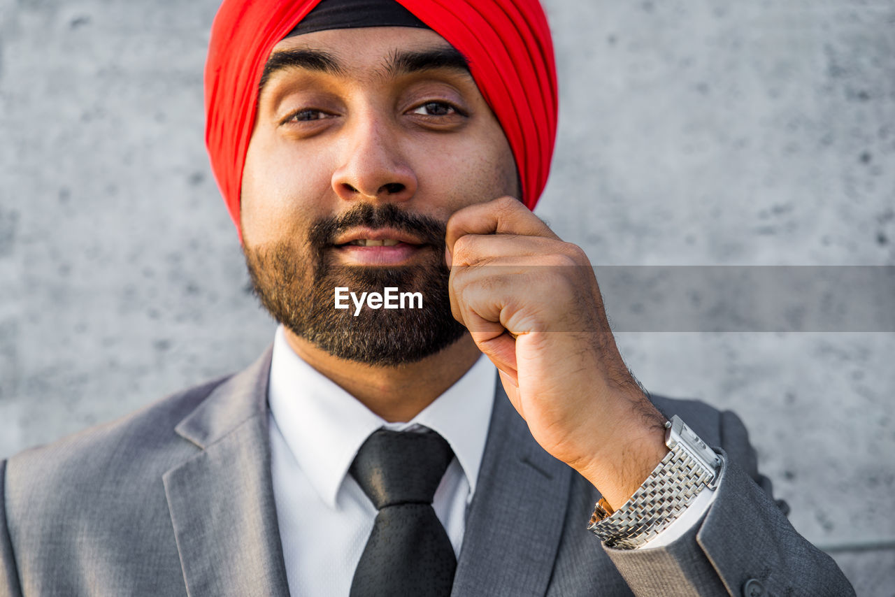 Close-up of businessman holding mustache while standing outdoors