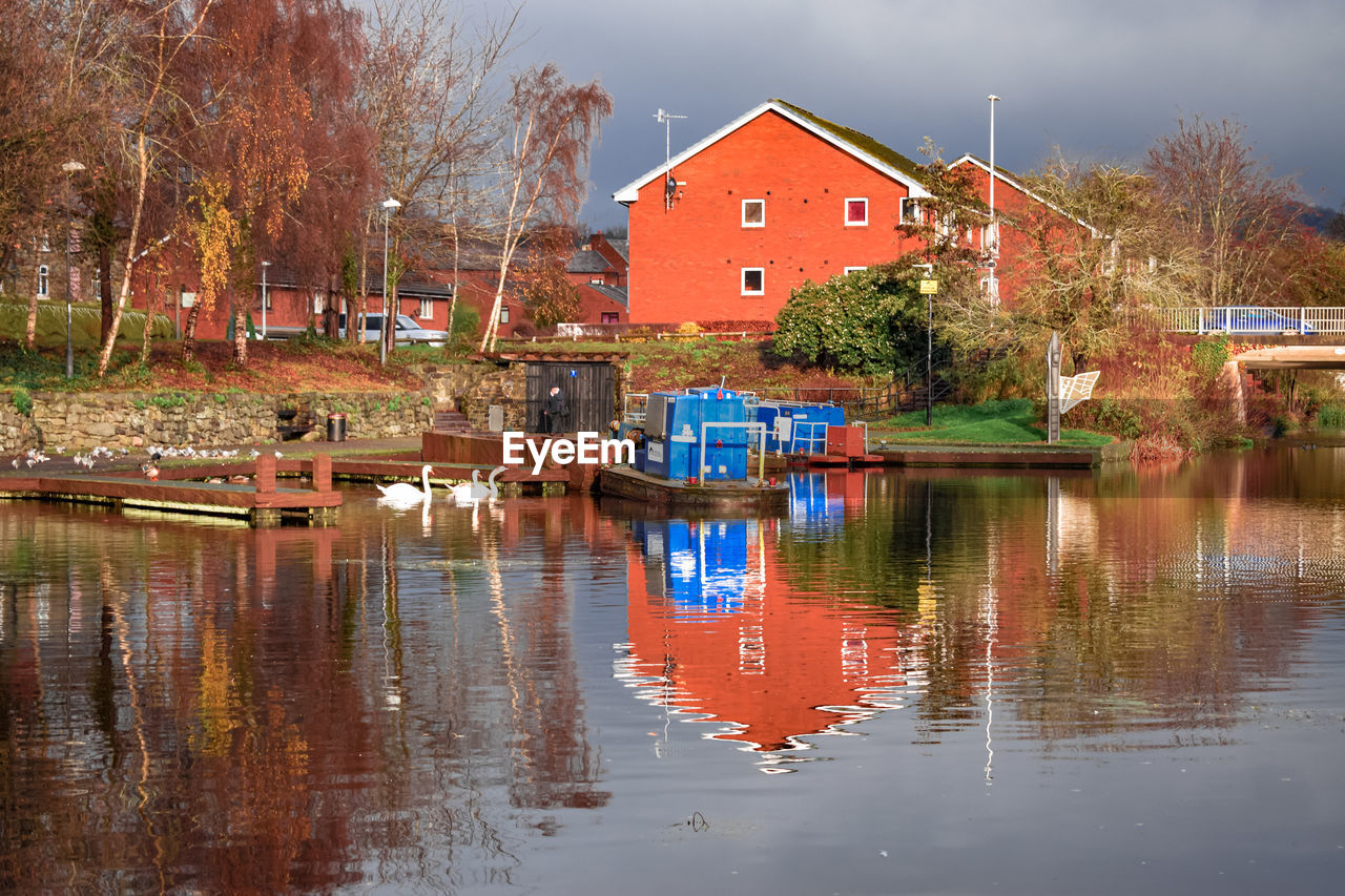 water, reflection, architecture, built structure, building exterior, building, river, house, nature, tree, autumn, waterway, nautical vessel, sky, residential district, plant, no people, transportation, multi colored, body of water, evening, outdoors, city, cloud, travel destinations, landscape, waterfront, day, beauty in nature, mode of transportation