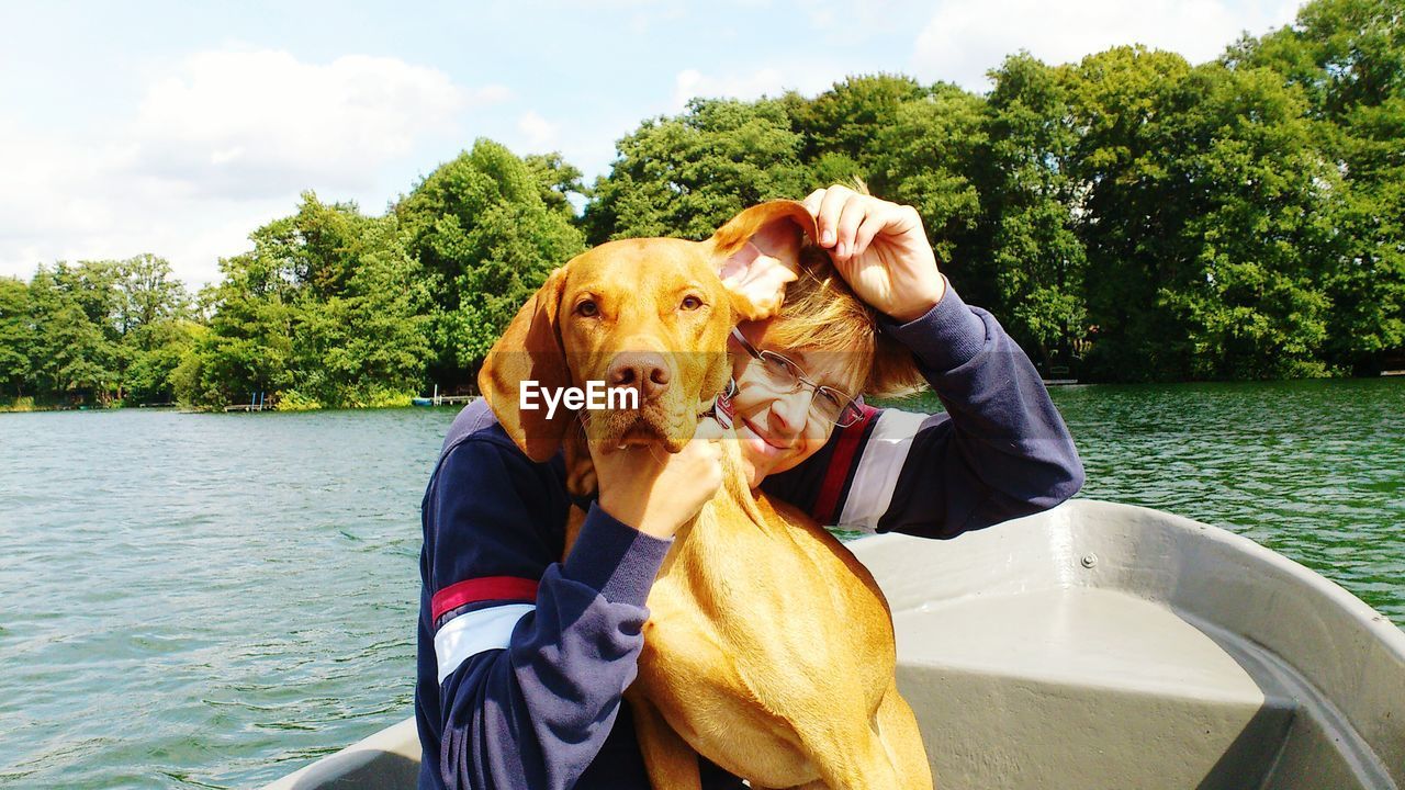 Portrait of woman with dog traveling in boat on lake