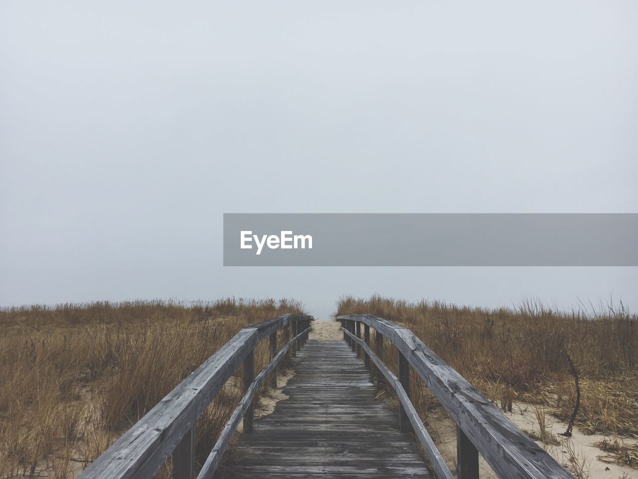 Boardwalk on field against clear sky