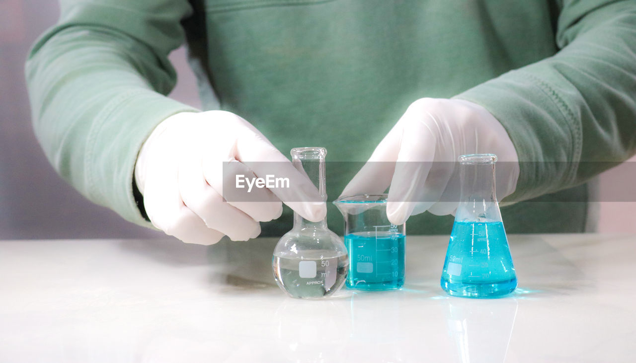 Midsection of man mixing chemicals in a laboratory 