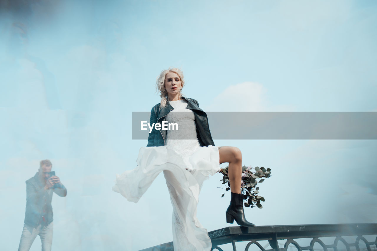 Low angle view of woman standing against sky