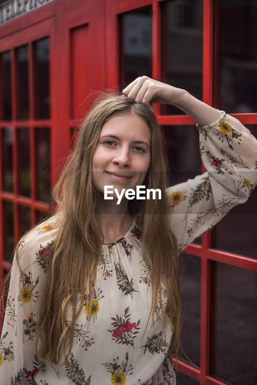 portrait of smiling young woman standing against building