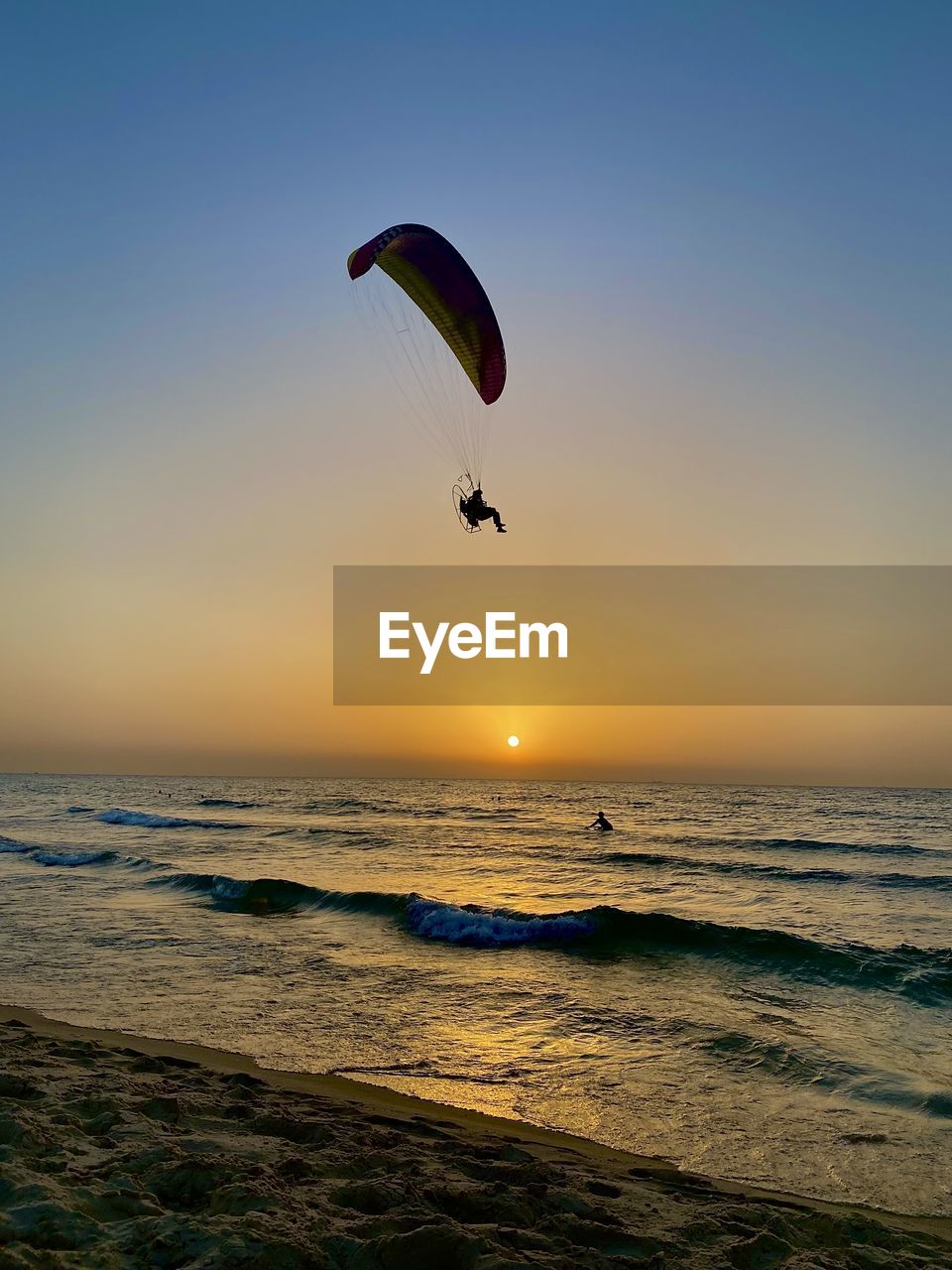 low angle view of person paragliding against sky during sunset