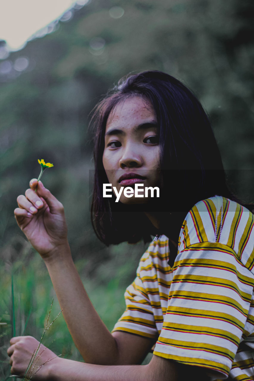 Portrait of young woman holding plant