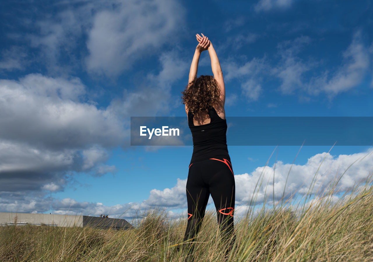 Rear view of woman standing on field against sky