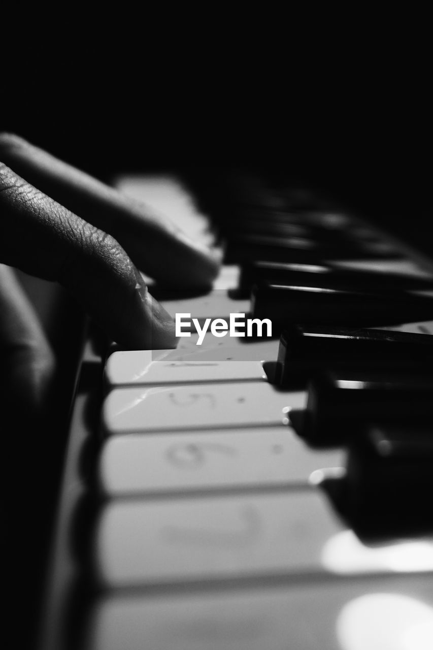 Close-up of hand playing piano