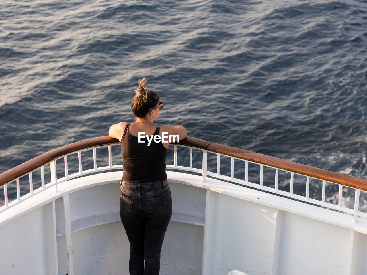 Rear view of woman standing on cruise ship sailing on sea